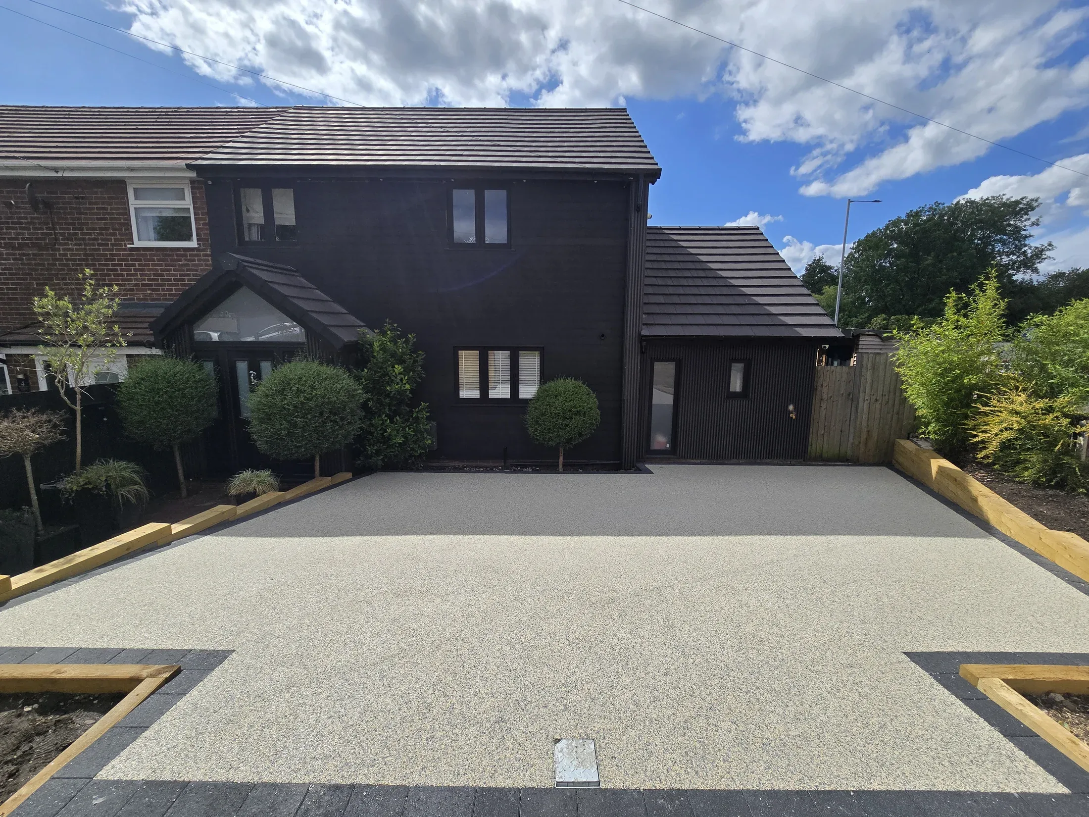 A finished pale resin bound driveway with dark edging outside a contemporary home