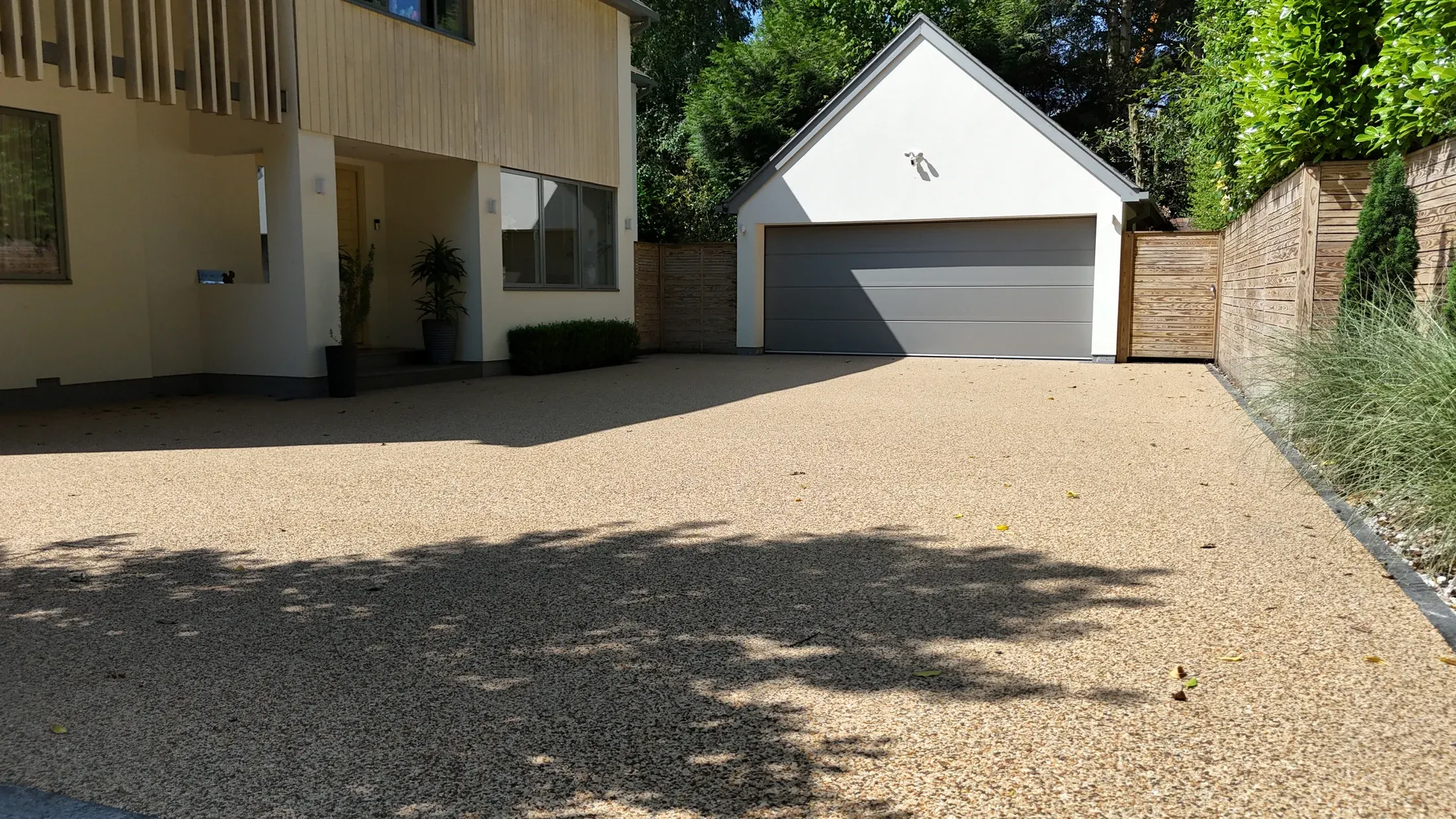 Finished pale grey resin driveway with a dark contrasting edge outside a garage