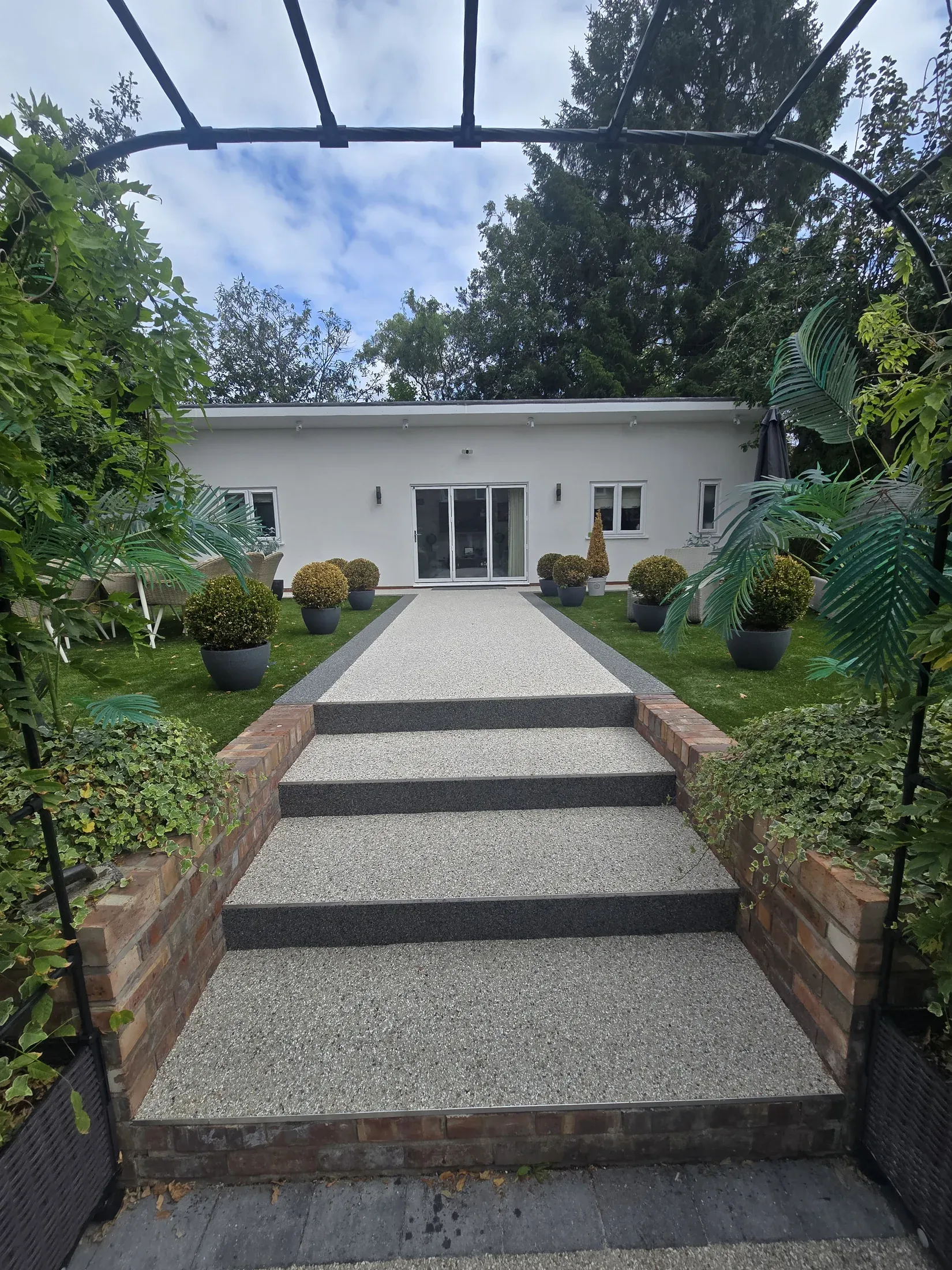 A pale resin path and broad garden steps leading through established planting