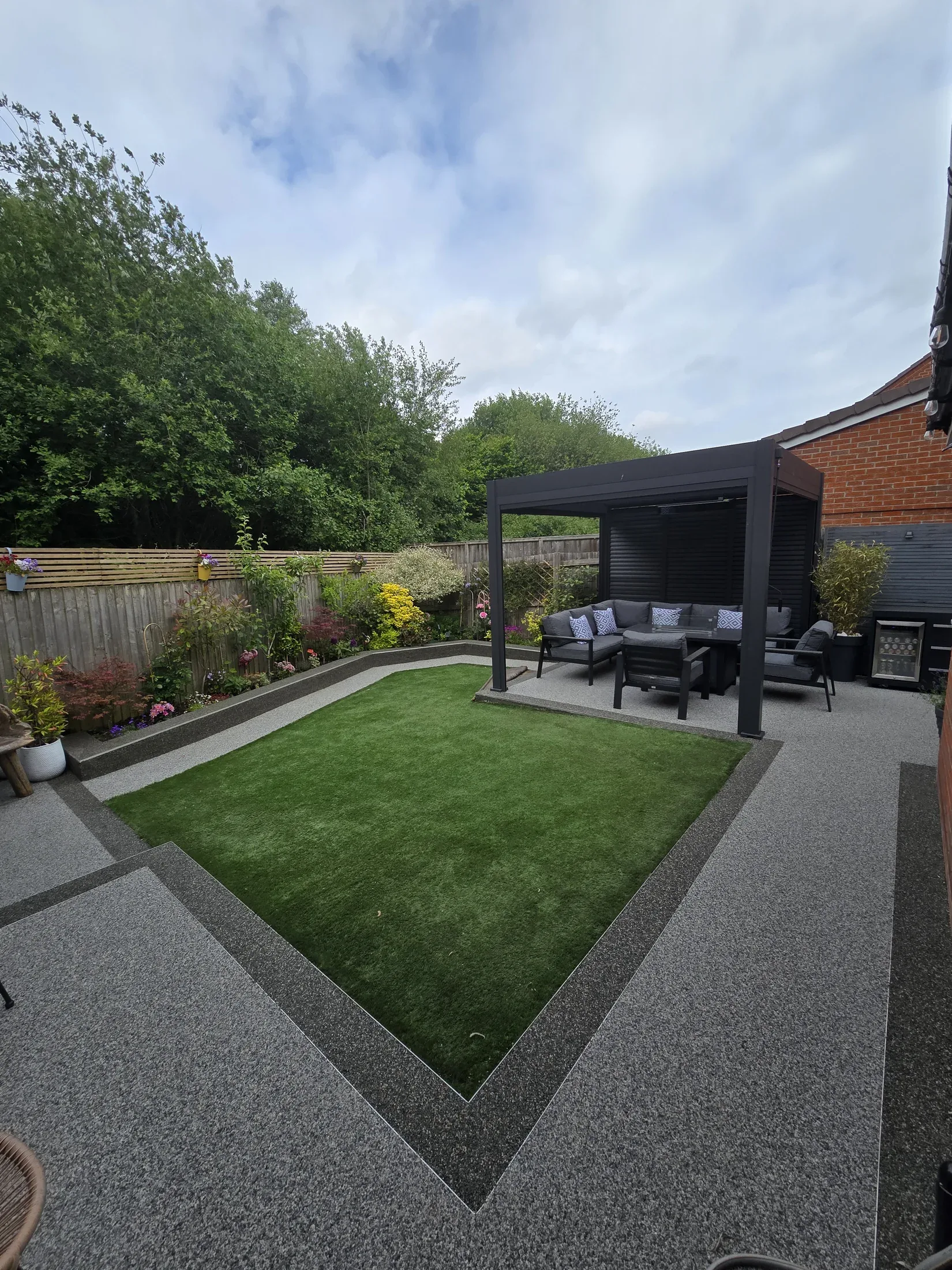 A finished two-tone resin patio framing a landscaped garden and lawn